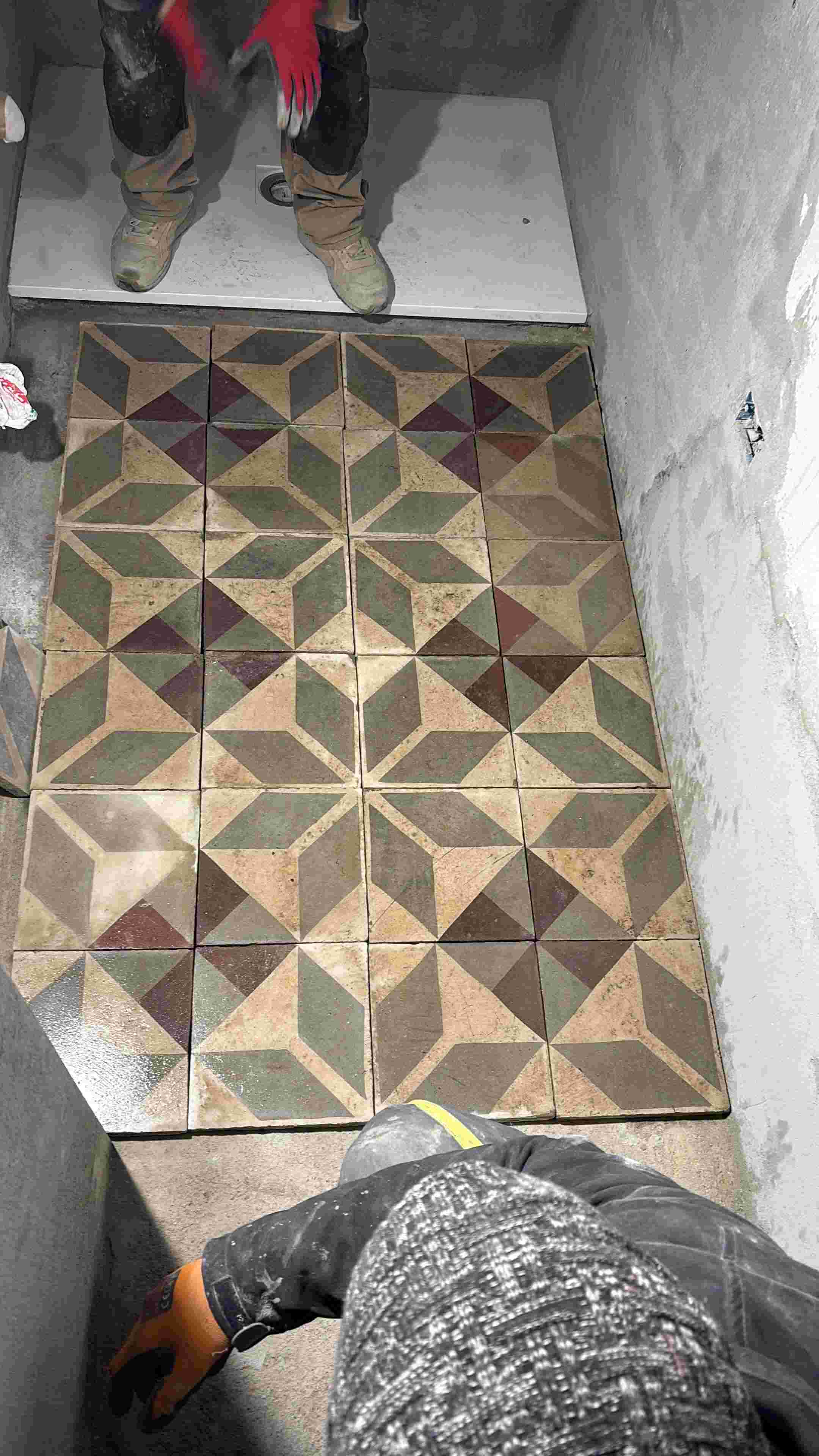 Artisans laying antique geometric floor tiles